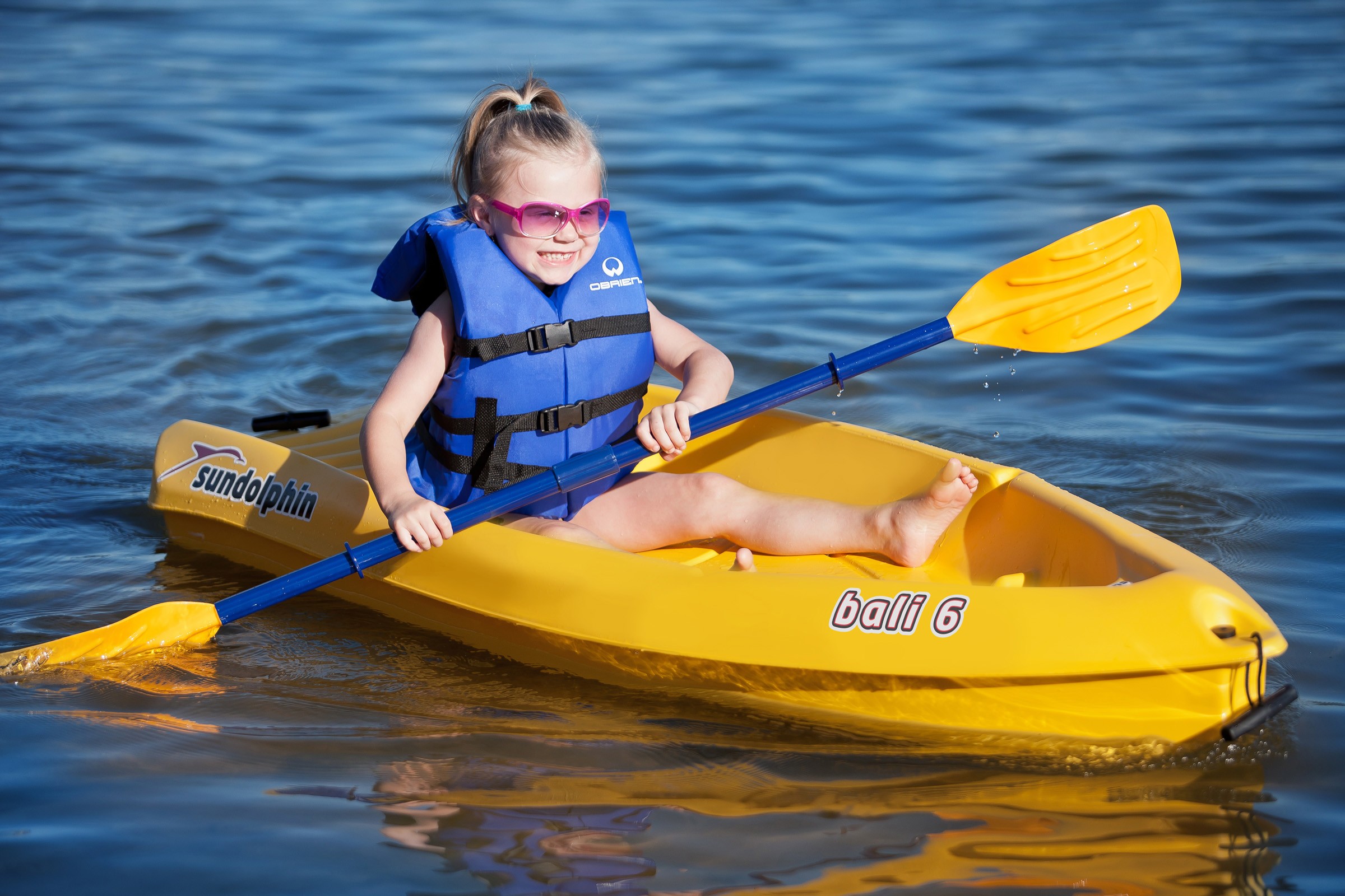 Kid paddling in a boat with sunglasses on