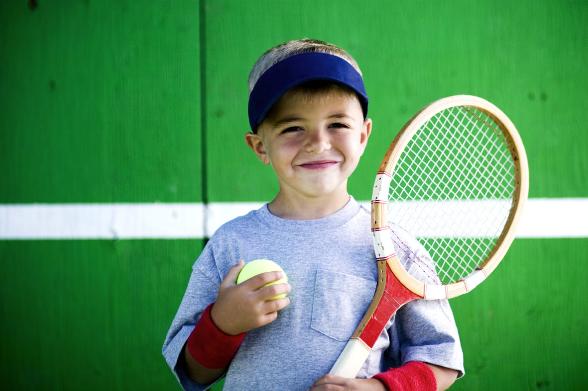 Kid holding a tennis ball and tennis racket