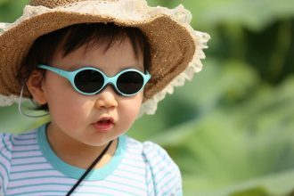 Child wearing hat and sunglasses for UV protection.